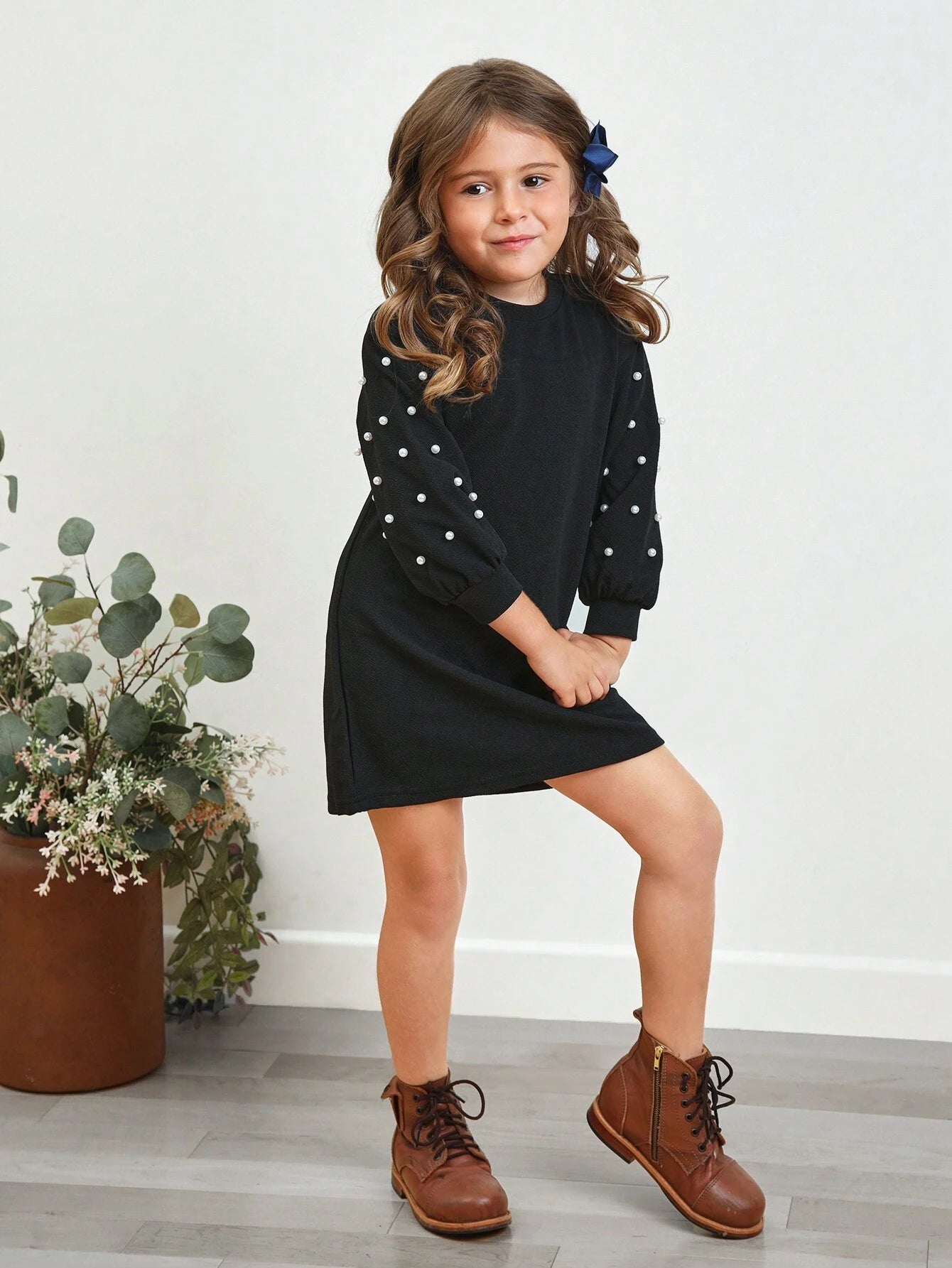 Detalle de las mangas tipo obispo con perlas del vestido negro para niñas.