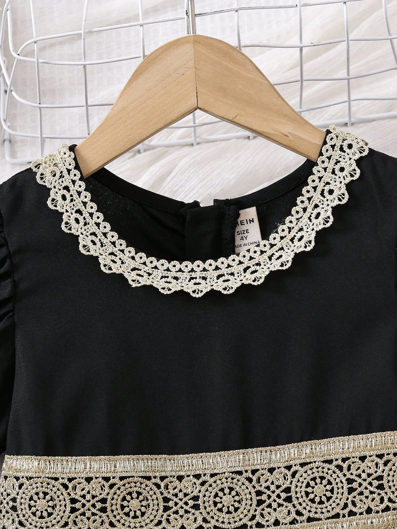 Primer plano del cuello redondo con encaje dorado.