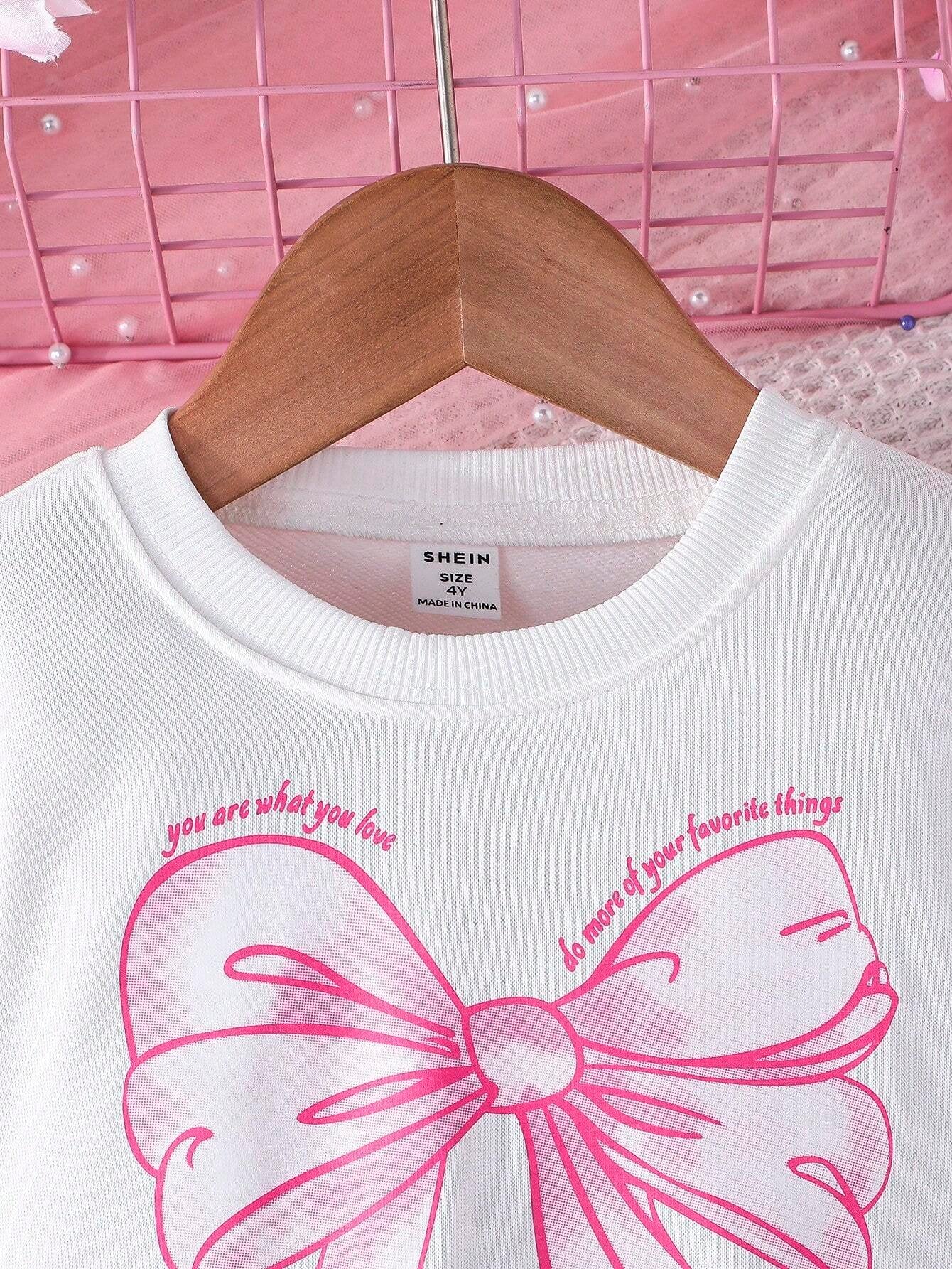 Detalle del estampado de lazo rosa en la sudadera del vestido para niñas.