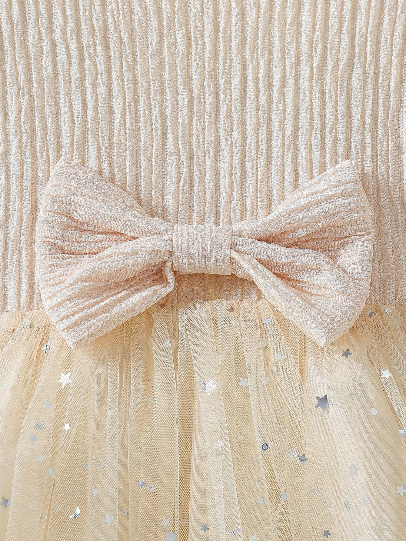 Detalle del lazo y fruncido en la parte superior del vestido albaricoque con tul y lazo para niña.