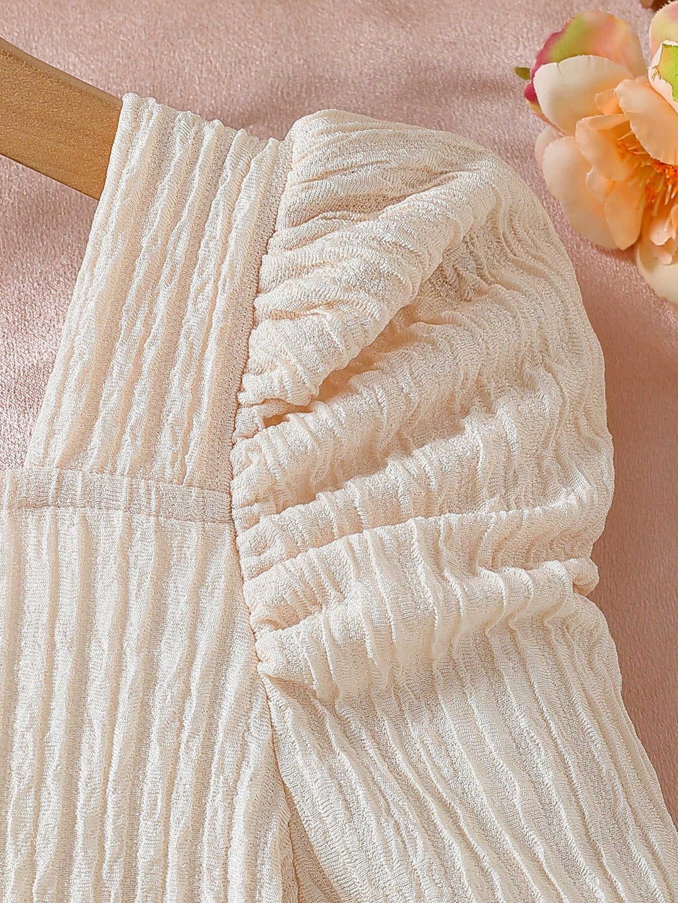 Detalle de la manga farol y textura fruncida del vestido albaricoque con tul y lazo para niña.