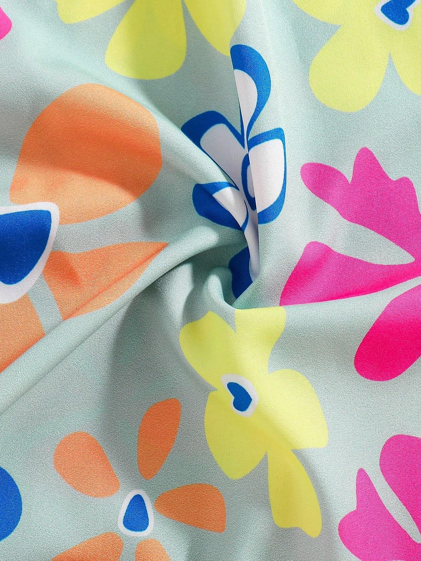Detalle estampado: Primer plano del estampado floral colorido del vestido verde con tirantes para niña.