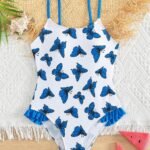 Traje de baño blanco con estampado de mariposas azules y volantes en los costados.