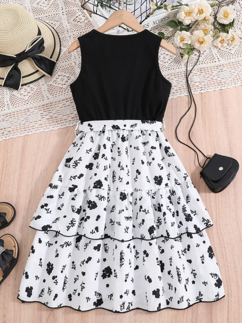 Vestido midi blanco y negro con cinturón para niña, vista trasera mostrando el diseño sin mangas y falda en capas.