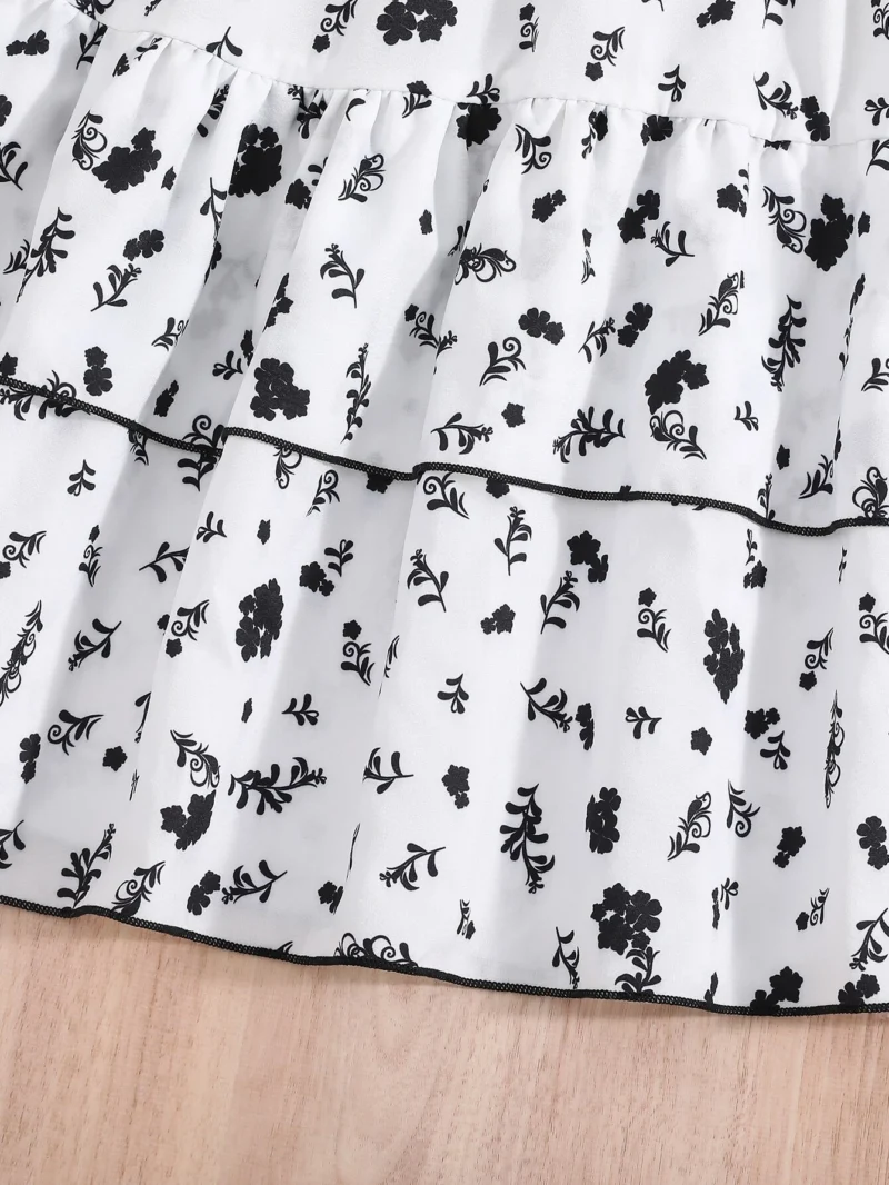 Detalle de la falda en capas con estampado floral del vestido midi blanco y negro con cinturón para niña.