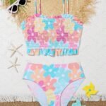 Bikini para niñas estampado floral con volantes, top smock y tirantes finos, acompañado de accesorios playeros.