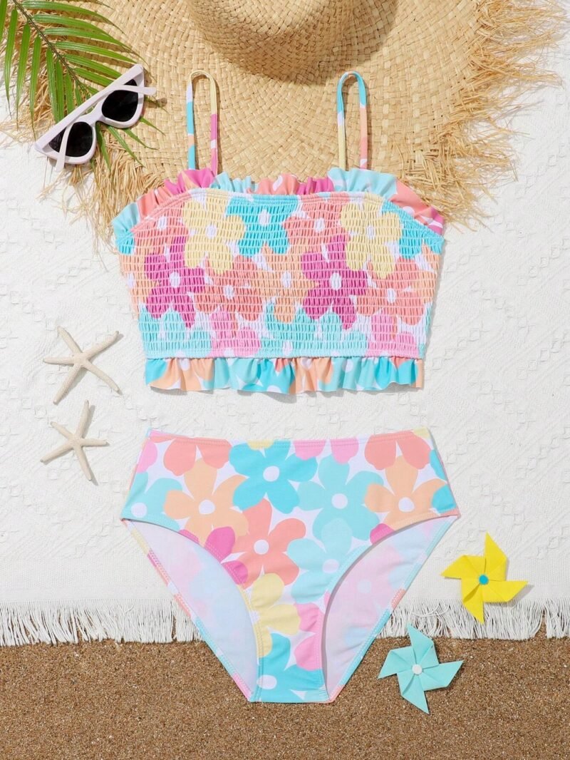 Bikini para niñas estampado floral con volantes, top smock y tirantes finos, acompañado de accesorios playeros.