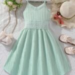 Vestido verde con tirantes finos y encaje para niñas, vista frontal sobre fondo decorativo.
