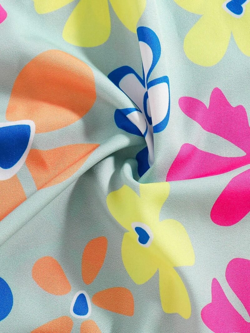 Detalle estampado: Primer plano del estampado floral colorido del vestido verde con tirantes para niña.