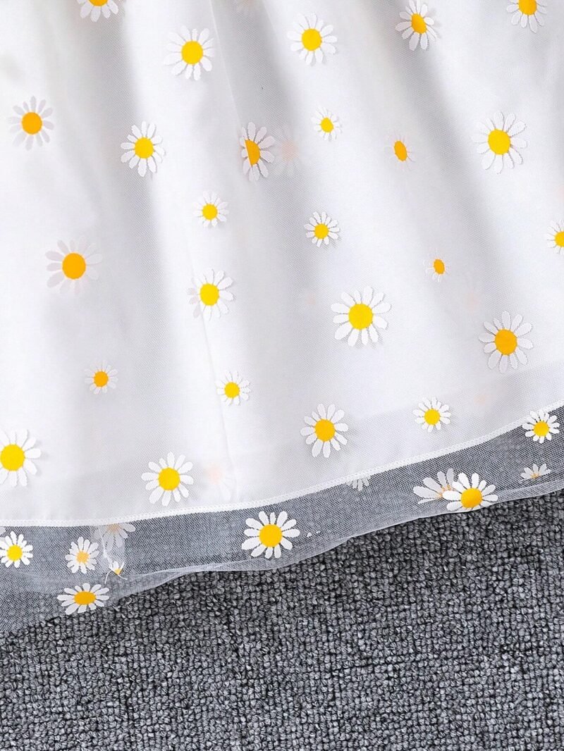 Primer plano del estampado de margaritas en la falda del vestido de tirantes para niñas.