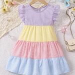 Vestido para niña multicolor con volantes en percha sobre fondo decorado.
