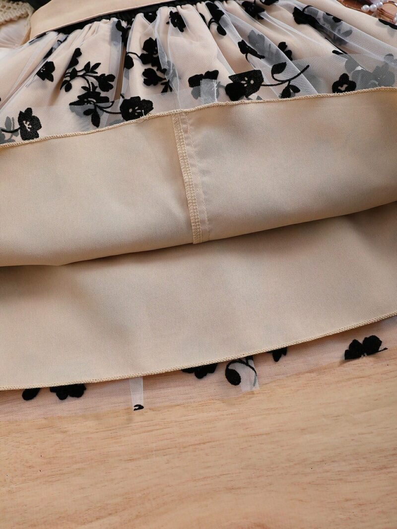 Detalle del escote redondo del vestido negro floral de gasa para niña.