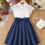 Vestido azul con encaje para niña, vista frontal mostrando detalles de la falda plisada y lazo satinado.