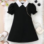 Vestido negro elegante para niñas con cuello camisero y mangas farol, acompañado de accesorios.