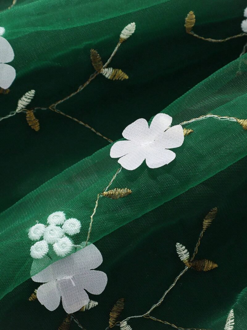 Primer plano de la falda con tul bordado y apliques florales del vestido verde oscuro con tul bordado para niña.