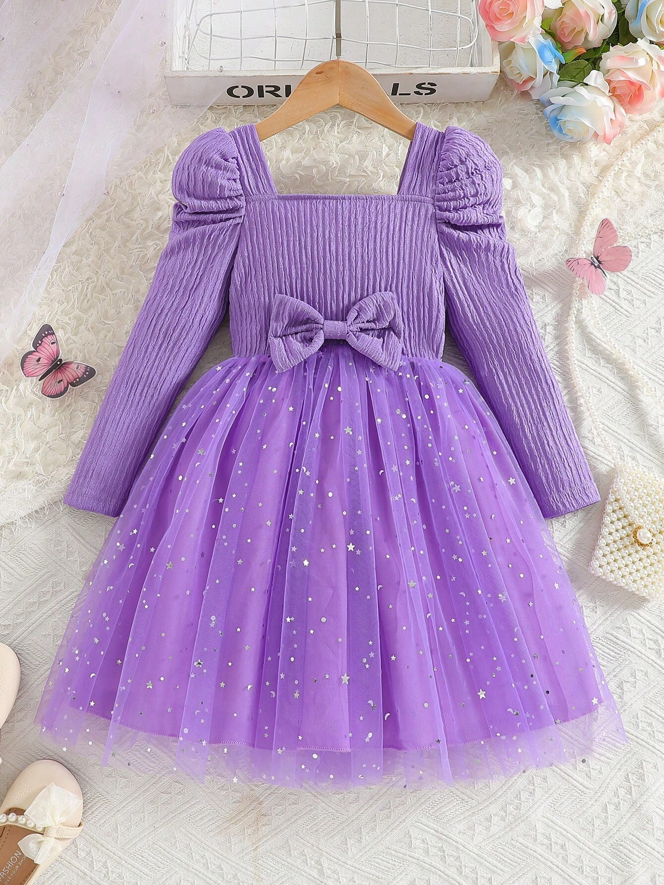 Vestido morado con tul y lazo para niña, vista frontal con falda brillante y mangas farol.