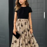 Vestido elegante para niña negro con falda floral beige en vista frontal